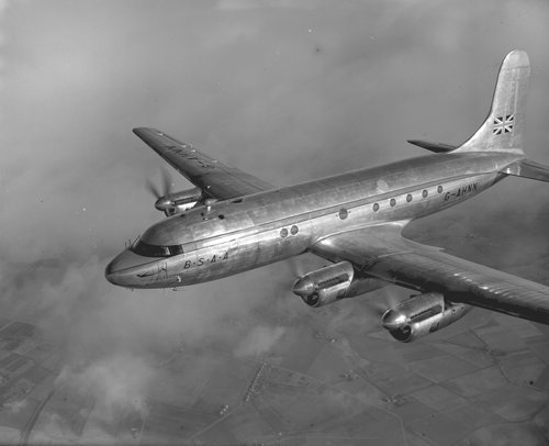 Schwarz-Weiß-Bild eines viermotorigen Propeller-Transportflugzeugs im Flug.