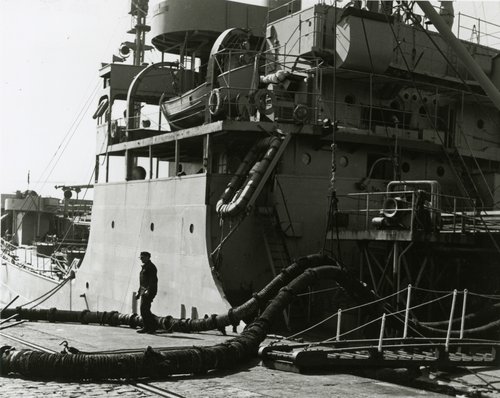 Ein Mann überwacht das Umpumpen von Treibstoff aus einem Tankschiff.