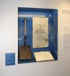 A shovel, a poster and a book in a display case. MHM Gatow Exhibition