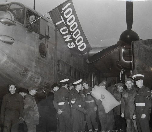 Eine Personengruppe neben einem großen Transportflugzeug.