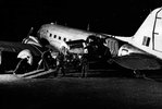 Schwarzweißfoto von Männern, die einen Motor durch die Tür eines Transportflugzeugs bewegen.